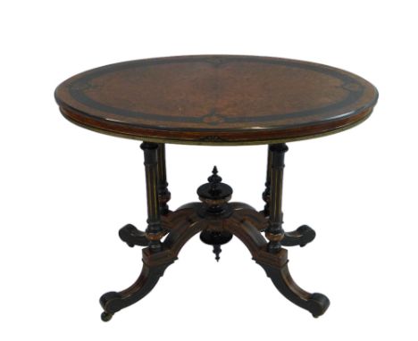 A late Victorian amboyna and ebonised salon table, of oval form, the line incised quarter-veneered top with gilt metal mount 