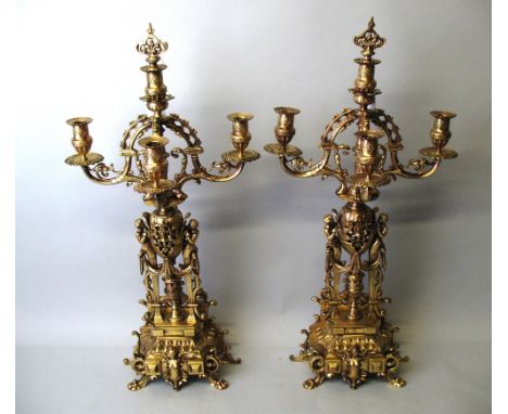 A pair of 19th century French polished brass four-light candelabra, of classical revival style, the stepped base with figural