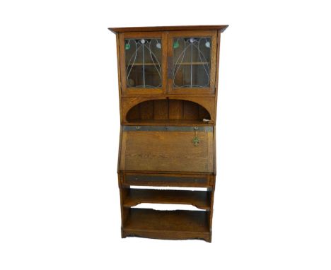 An early 20th century Arts and Crafts oak bureau/bookcase, with beaten copper strapwork mounts and lockplates, the plain pedi