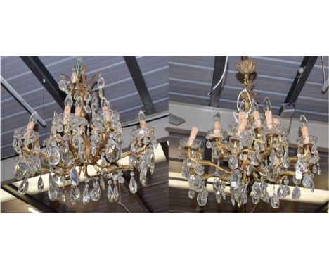 A pair of sixteen light gilt brass lustre drop chandeliers, with scroll and leaf cast arms
