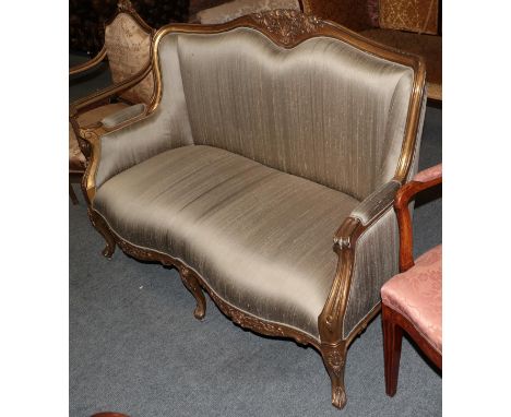 A French gilt framed sofa with floral carved crest and scroll carved down swept arms raised on similarly carved legs 