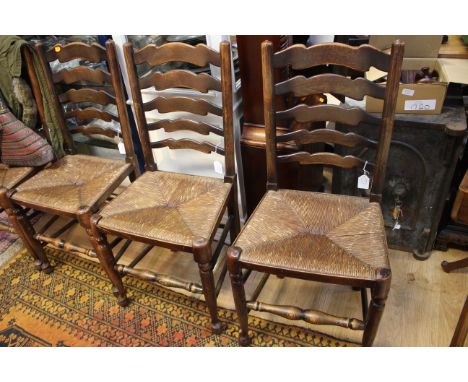 A set of four oak ladder back chairs, each with rush seats, standing on turned legs, (4)