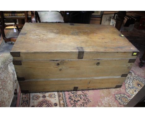 A late 19th Century pine trunk, with iron bound corners, carrying handles to sides