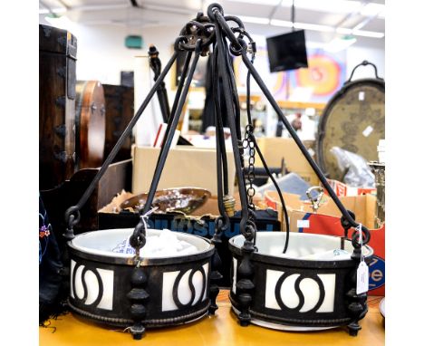 A pair of Arts and Crafts wrought iron pendant light fittings, reticulated drum form suspended from four bars 