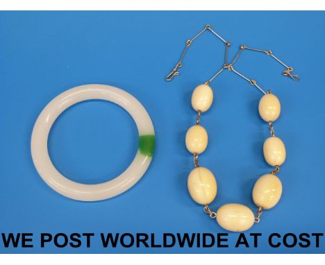 A yellow metal necklace strung with seven ivory beads together with a jade type bangle 