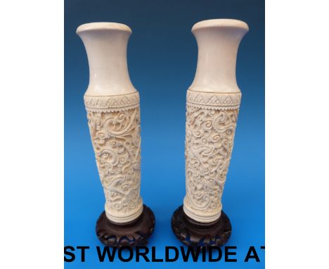 A pair of Chinese carved ivory vases on wooden stands (24cm tall)