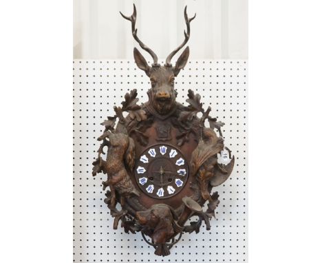 19th Century carved black forest pendulum wall clock having a round clock to the centre with enamelled roman numeral panels t