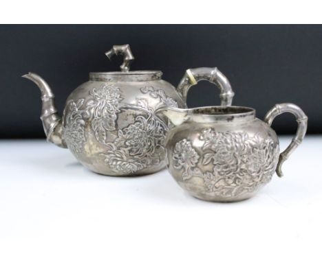An antique Chinese silver teapot cast with cherry blossom decoration and bamboo style handles and finial, together with match