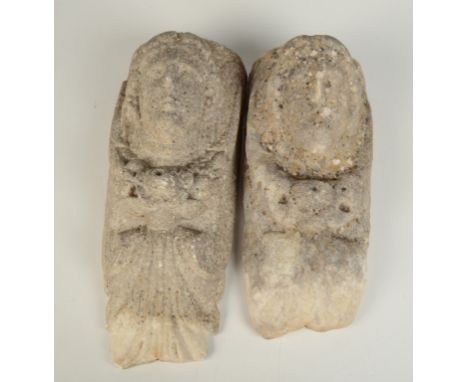 A pair of marble corbels, each carved with a portrait face in medieval style, lengths 43cm and 39cm.