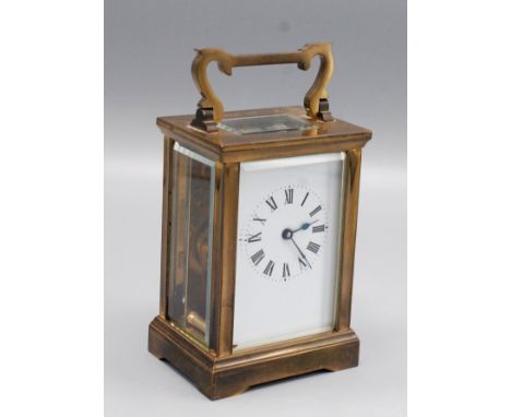 A brass carriage clock, the swing handle above four bevelled glass panels, rectangular white enamel dial with roman numerals,