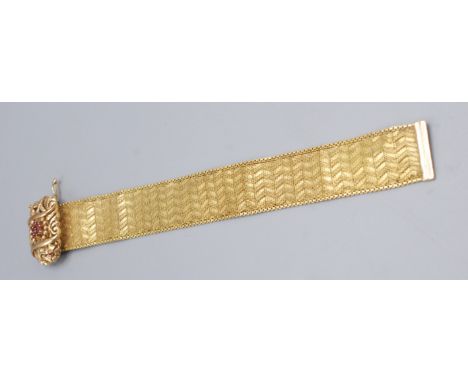 An 18ct gold Italian chevron decorated mesh bracelet with a floral and scroll ruby set panel, 65.18g.
