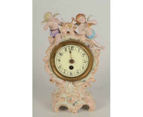 A German porcelain mantle clock, with a 7cm diameter dial, the floral painted case surmounted by winged cherubs, height 21cm.