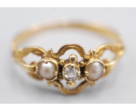 An early Victorian gold ring, set two pearls and a diamond amongst engraved scrollwork.