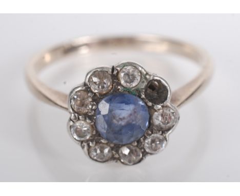 A gold ring, set a sapphire and white stone cluster.