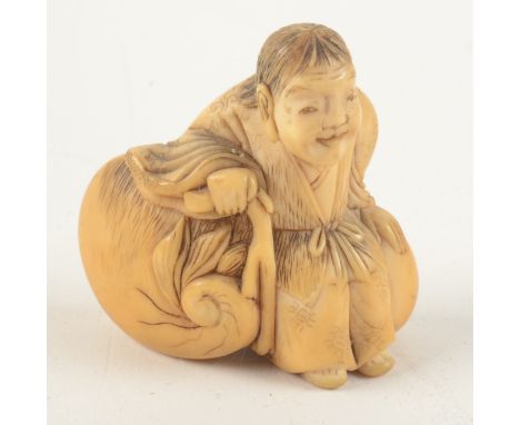 A Japanese ivory netsuke of a peasant seated on a large gourd, height 4.2cm, width 4.3cm.