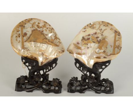 A pair of Chinese mother of pearl shells on stands, 19th century, gilt decorated to each side with peacocks and birds, trees,