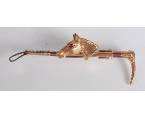 A horse racing 9ct gold brooch in the form of a crop mounted with a horses head with ruby eyes.    Condition report:  5.7g.