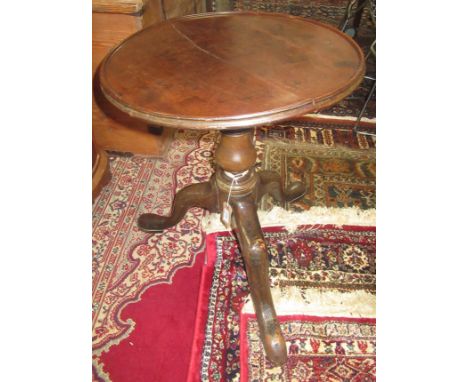 A George III mahogany tripod table, the dished top on a baluster stem and downswept supports, height 57cm, diameter 49cm.