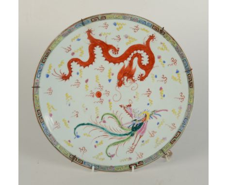 A Chinese porcelain charger, the white ground decorated with a dragon chasing the flaming pearl opposing an exotic bird and n