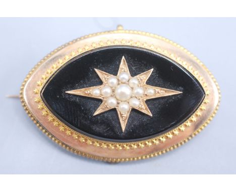 A Victorian gold elliptical brooch with pearl set central star on black onyx. 