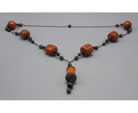 A silver filigree and amber necklace with three pairs of large graduated amber beads and a cylindrical amber pendant bead, th