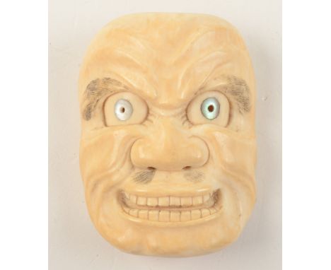A Japanese carved ivory okimono Noh mask of a smiling man, mother of pearl decorated eyeballs, length 7.5cm, width 6cm. 