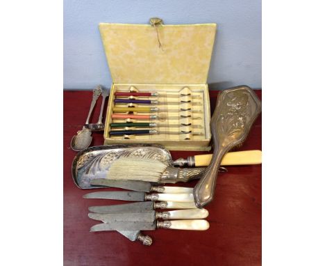 An assortment of plated and silverware inc. hairbrush mother of pearl handled knives etc.