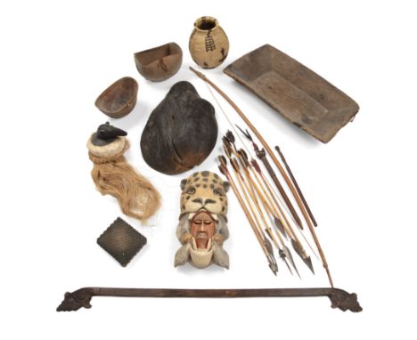 A collection of tribal artifacts to include bowls an animal mask and a bow and arrows.