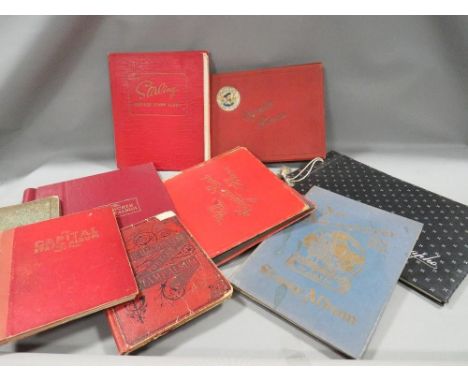 A tray of vintage empty cigarette card and stamp albums 