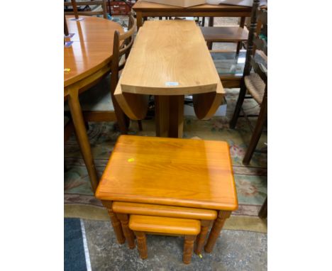 A solid light oak drop leaf table together with a pine nest of tables 