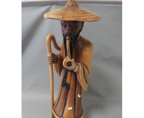 A large carved wooden figure of a man smoking a pipe 