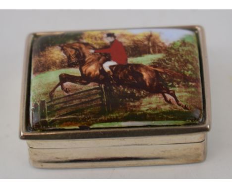 A silver pill box marked .925 with hunting scene depicting man on horseback jumping over a gate.  In good condition.
