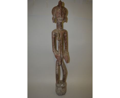 A CARVED WOODEN DEBLE, from the Ivory Coast, male figure holding an axe with horned headgear, approximate height 110cm x 20cm