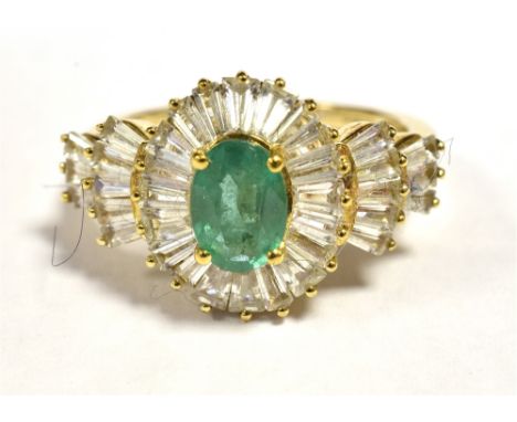 9CT GOLD EMERALD CLUSTER RING The faceted Oval Emerald measuring 7 x 5mm in a clear stone accent mount with fanned shoulders.