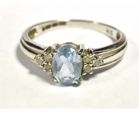 9CT WHITE GOLD SAPPHIRE AND DIAMOND DRESS RING The oval faceted light blue sapphire flanked by three small round cut diamonds