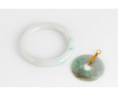 Possibly moss-on-stone jadeite, carved as a continuous hoop, inner diameter approximately 6,2cm; and A Jade-like Stone Pendan