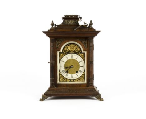 A 19th Century German mantle clock, the dial with Roman numerals surmounted by a brass putti, in a wooden case, supported on 