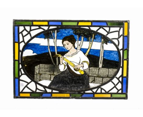 An early 20th Century stained glass panel,  with central oval image of a seated young lady playing the lute, with stylised tr