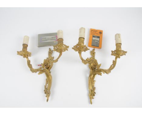 A pair of gilt metal two branch wall lights, of carved scrolling form, length 39cm, together with an adjustable leather shoot