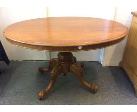 A Victorian Mahogany loo table, plain oval top with a turned bulbous column raised on a carved quadriform base and brown cera