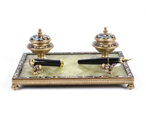 A late 19th/early 20th Century gilt metal and champlevé enamel desk stand set, with a stone base supporting two inkwells and 