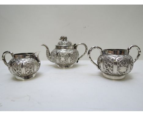 An early 20th century Indian, white metal three piece tea set of small boulbous proportions with floral, foliate and bird emb