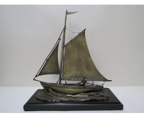 A 1930s plated and patinated metal model of a clinker sailing boat on a naturalistic base and ebonized plinth, 13 3/8 high