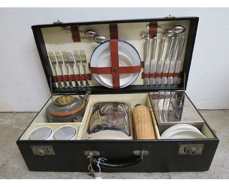 An early 20th century Coracle black faux leather clad picnic hamper enclosing cutlery, a kettle and burner, white glazed cups