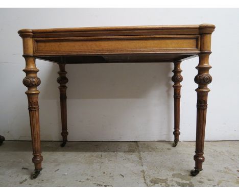 A late Victorian oak card table, the foldover top with turreted corners enclosing a green baize surface on carved, fluted, tu