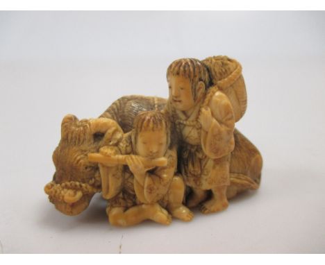 Tomochika, a Japanese ivory netsuke of two figures with a Water Buffalo, signed to the underside  