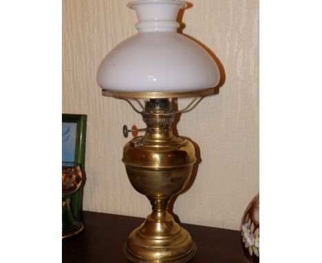 A brass oil lamp with white glass shade.