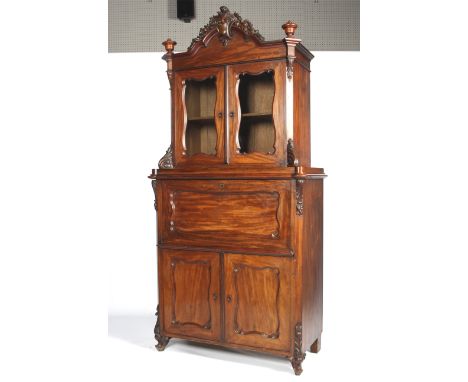 A Victorian mahogany secretaire bookcase. With carved fruiting and acanthus scroll arched cresting and urn finials above pane