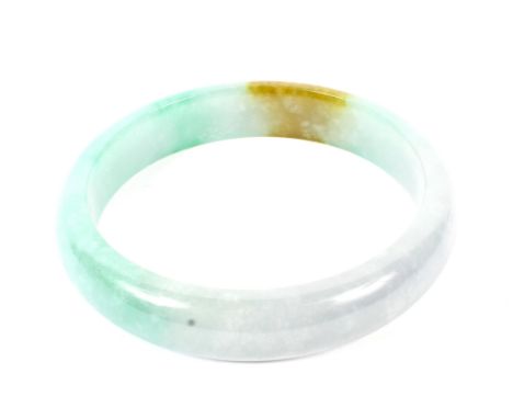 A Chinese light-green mottled hardstone bangle, probably jadeite. With a small section of light brown colouration, the intern