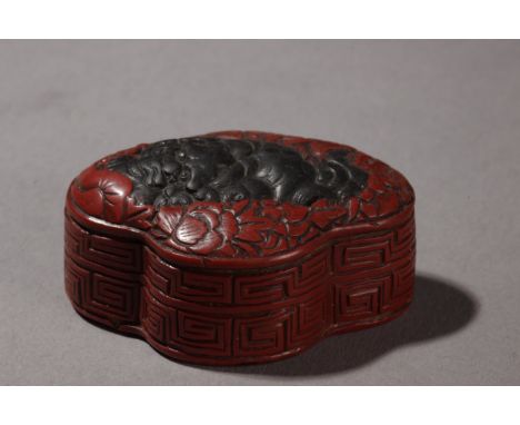 A mid 19th century Japanese netsuke manju. In red and black lacquer on carved wood depicting a Shishi sorrounded by a flowery